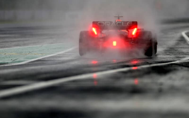 a red race car driving on a wet track