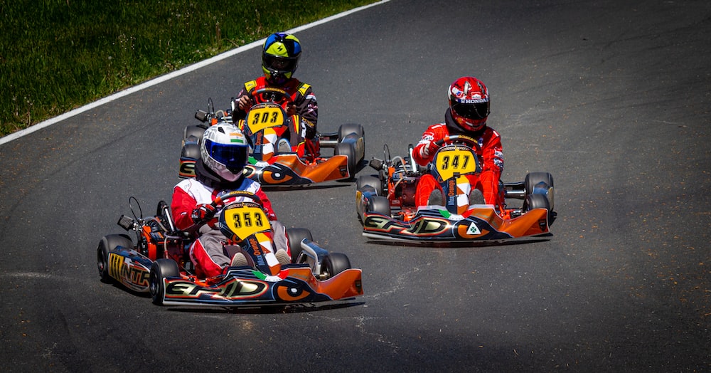three people racing go kart cars on a race track