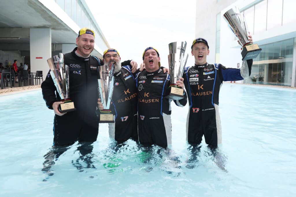 a group of people standing in a pool holding trophies