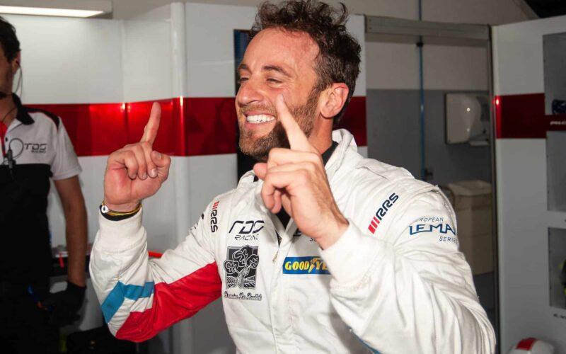 a man in a racing suit giving a thumbs up