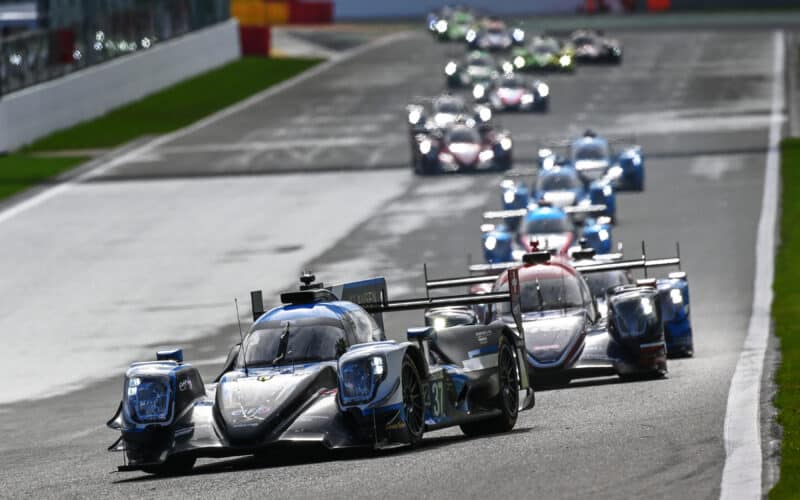 a group of racing cars driving down a race track