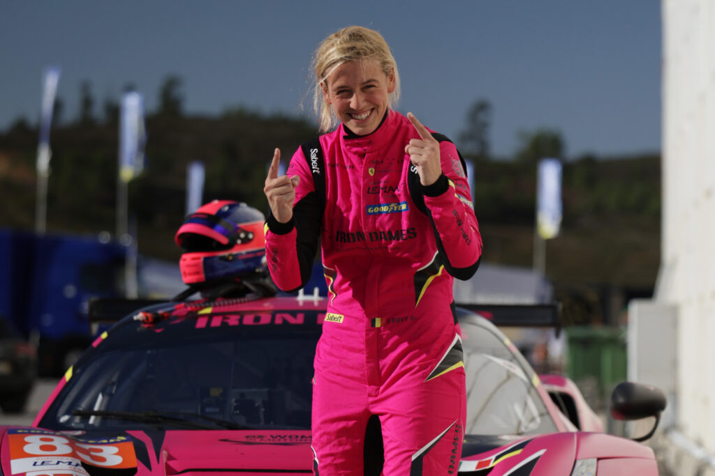 a woman in a racing suit giving a thumbs up