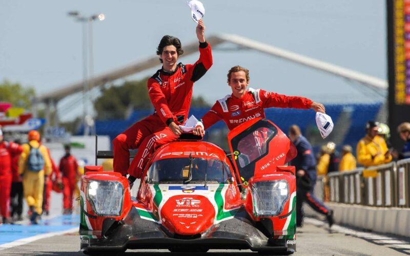 a couple of men riding on the back of a red car