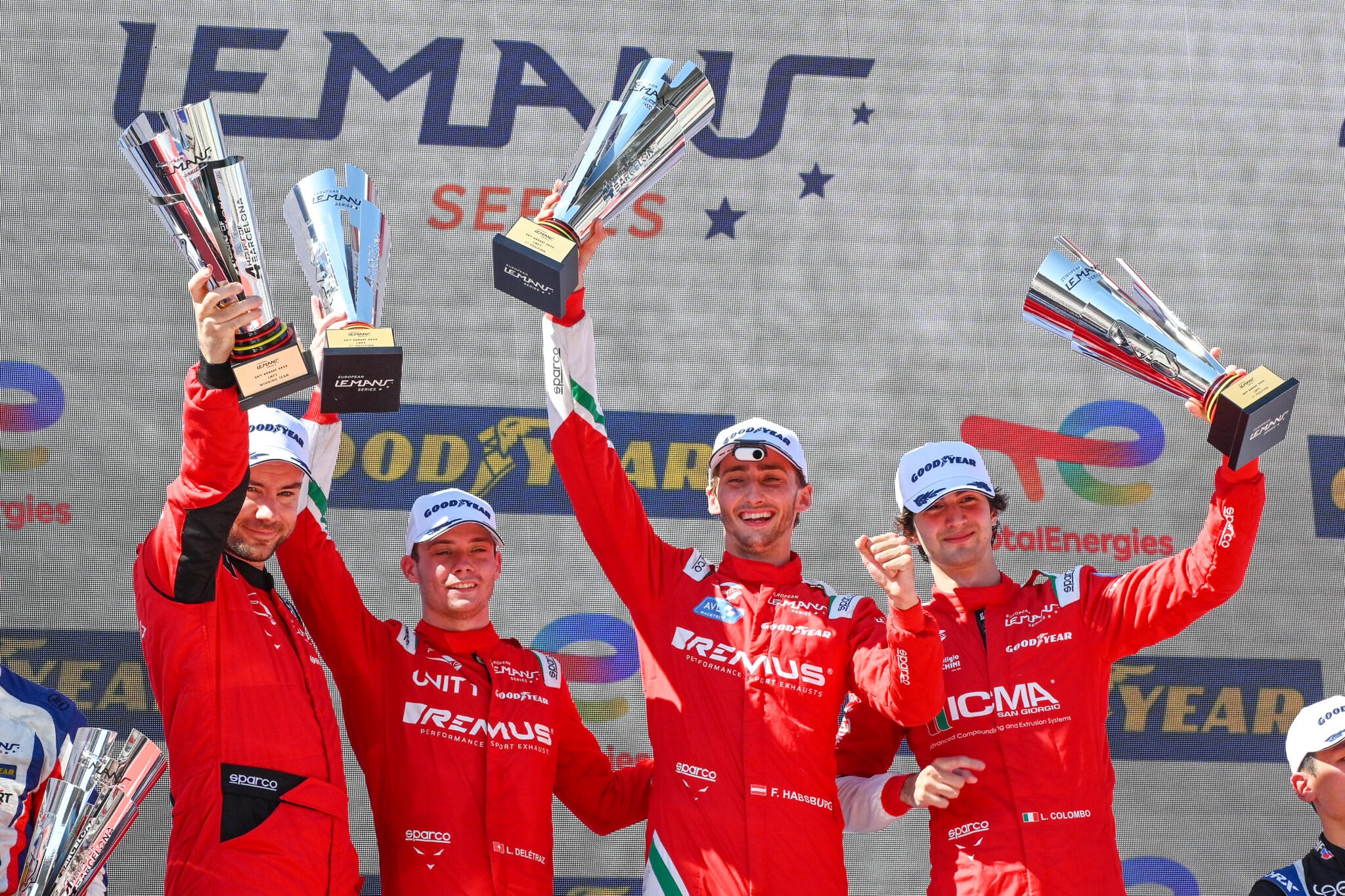 a group of men standing on top of a podium holding up trophies