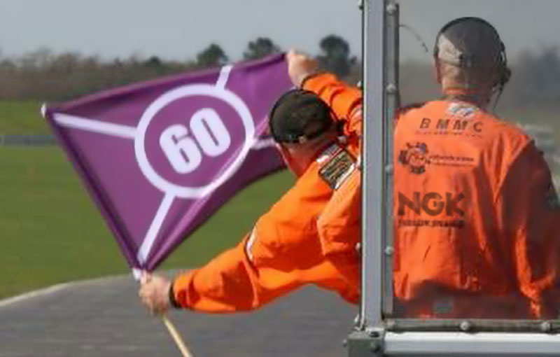 a man in an orange jacket holding a purple flag