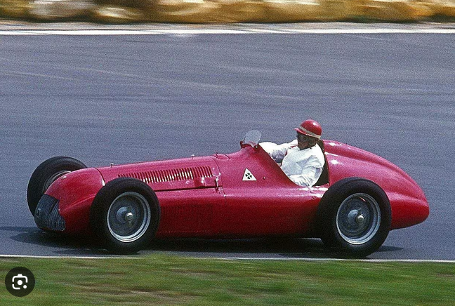 a man driving a red race car on a race track
