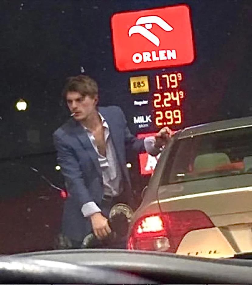 a man standing next to a car at a gas station